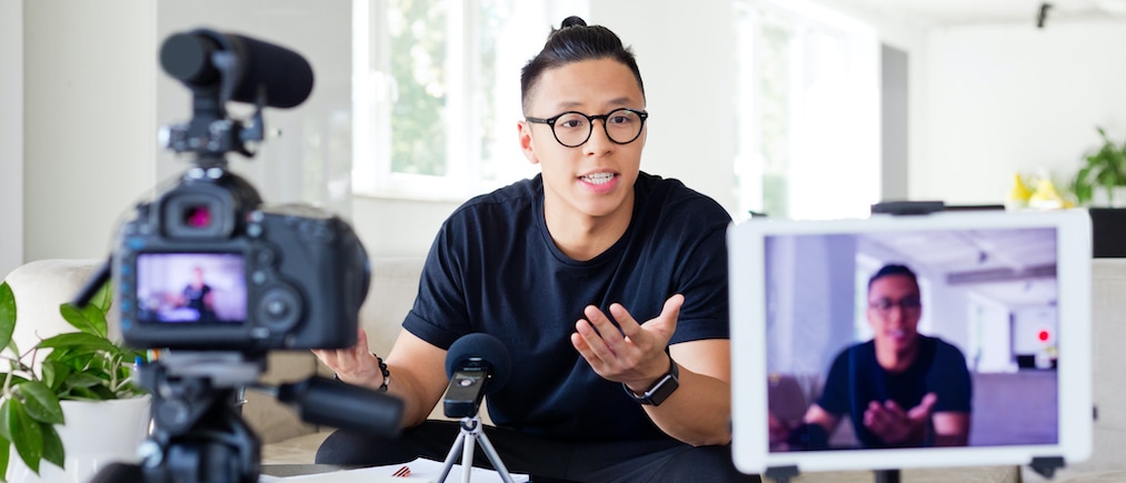 Handsome asian young man making a video blog. Male vlogger recording content on digital camera.