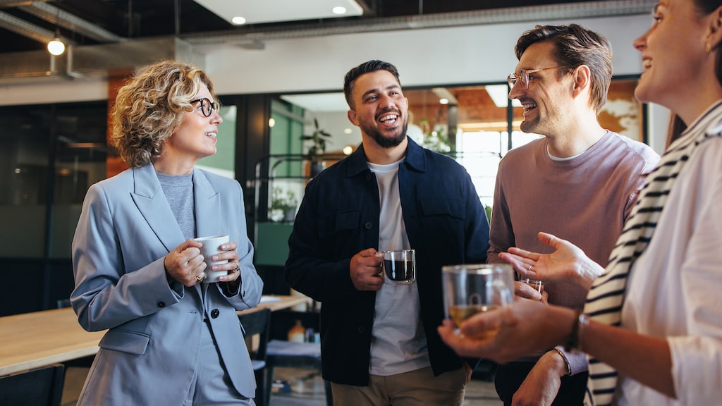 Happy colleagues having a coffee break in an office. Group of business people having a conversation in a workplace. Business professionals working in a startup.