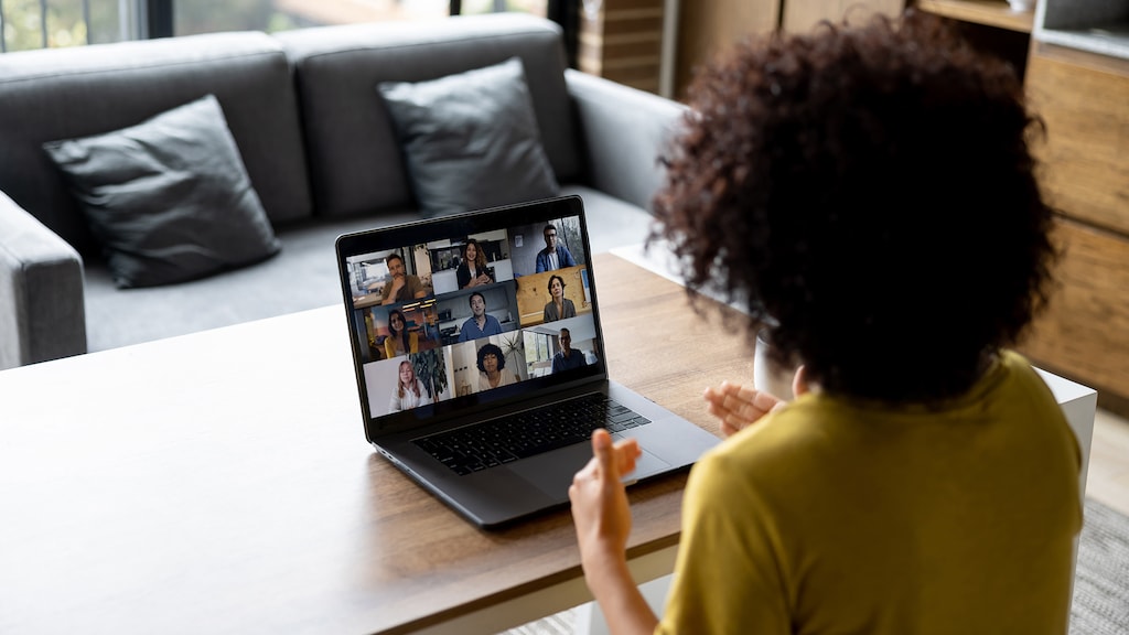 Latin American woman talking to some colleagues in an online business meeting while working at home - business video call concepts
