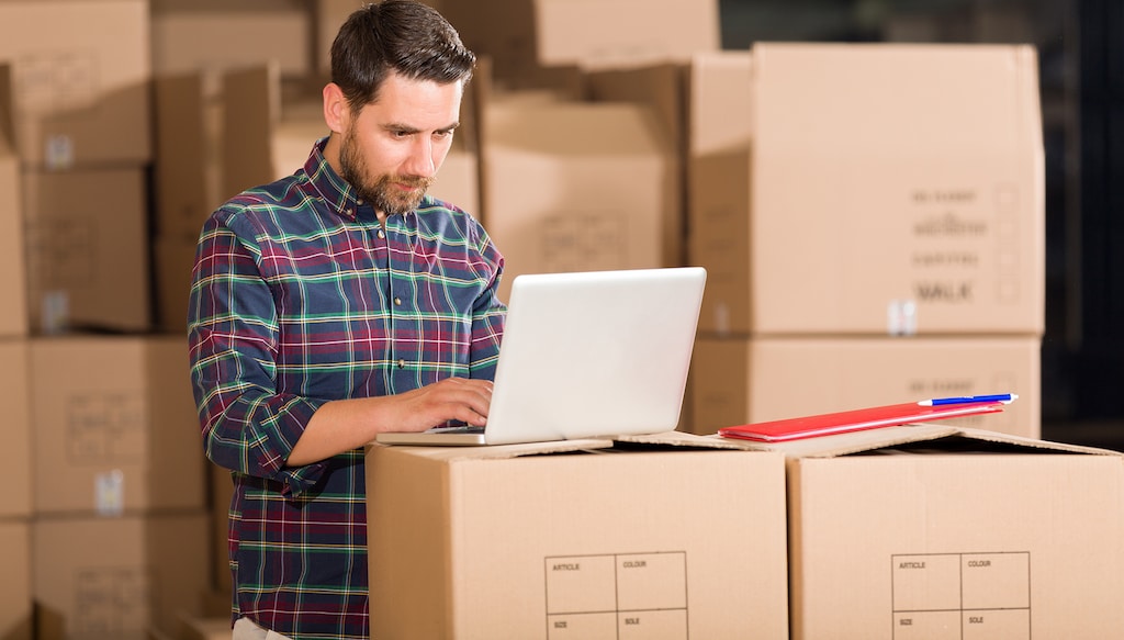 Young businessman working with laptop in factory.